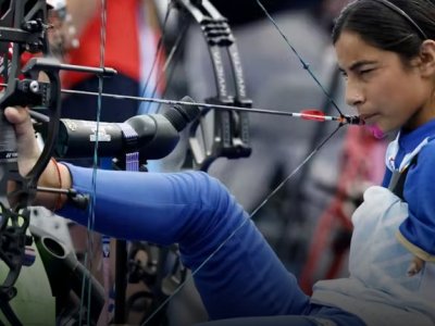 a woman sits in a chair and draws a bow with her foot and mouth